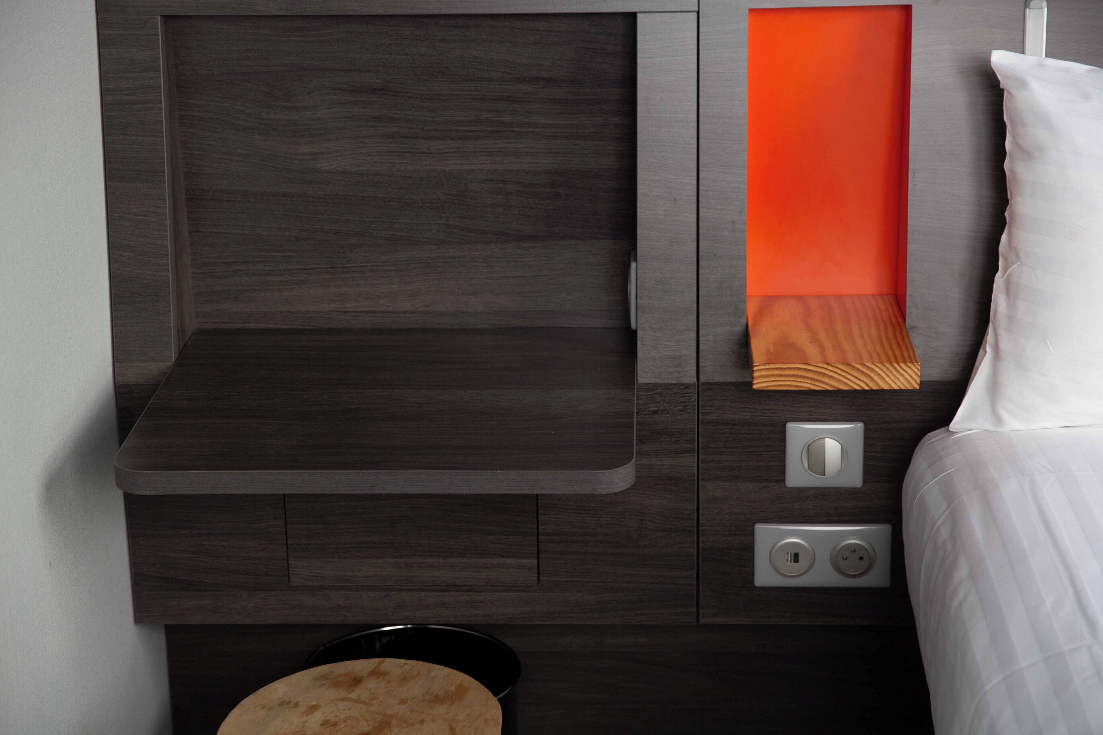 Une chambre moderne dotée d’un bureau intégré, d’une table de chevet et d’une petite table à côté du lit.