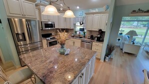 A modern kitchen with granite countertops, stainless steel appliances, and a central island. - 3/2 w/ Golf Cart in The Village of Santiago with Golf Course View! (The Villages)