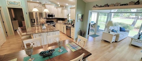 A spacious kitchen with a central island, white cabinetry, and a dining area with a wooden table.