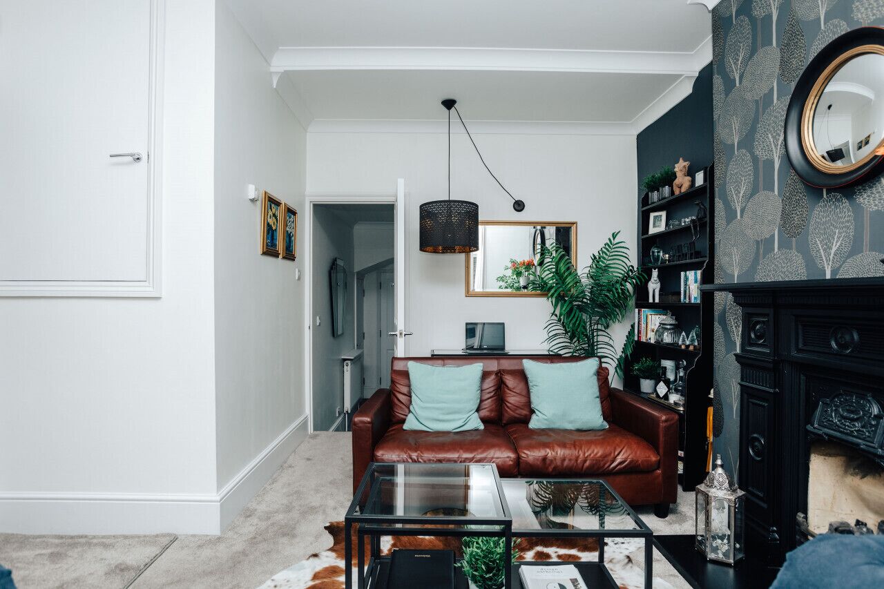 A living room with a leather sofa, a glass coffee table, and a bookshelf.