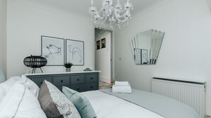 Ein modernes Schlafzimmer mit einem großen Bett, einem Schminktisch, einem Spiegel und Kunstwerken an der Wand.