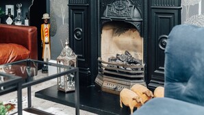 Ein gemütliches Wohnzimmer mit Kamin in Schwarz, einem Glastisch und einem roten Ledersofa.