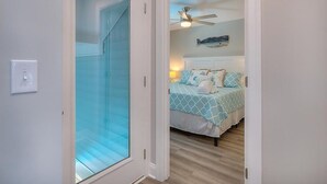 Un dormitorio con cama, ventilador de techo y un adorno de pez colgado en la pared.