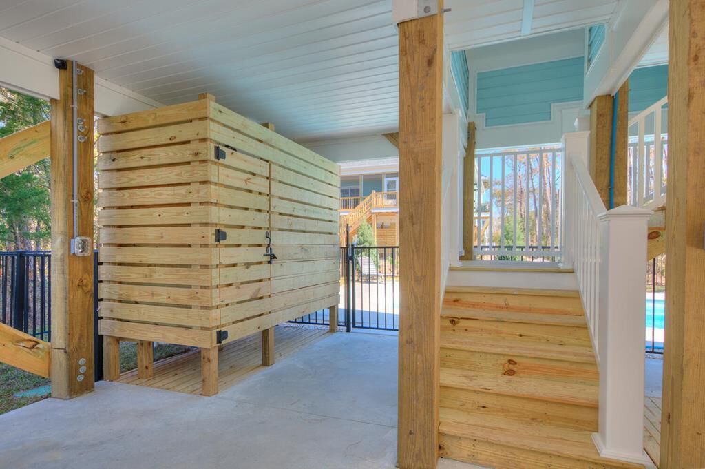 A covered wooden deck with a staircase leading to a balcony.