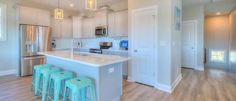A modern kitchen with white cabinets, stainless steel appliances, and a central island with bar stools.