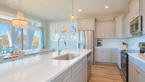 Una cocina moderna con armarios blancos, electrodomésticos de acero inoxidable y una isla grande con un lavamanos.