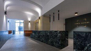 A modern lobby with a marble reception desk, a curved ceiling, and a glass entrance. - Torino in corte by Wonderful Italy (Torino)