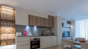 A modern kitchen with built-in appliances, a dining area with a table and chairs, and a window with sheer curtains. - Torino in corte by Wonderful Italy (Torino)