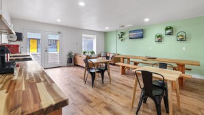 A spacious room with a wooden dining table and benches, a sofa, and a kitchen area with a red appliance. - Tahoe Mountain Inn #1 (South Lake Tahoe)