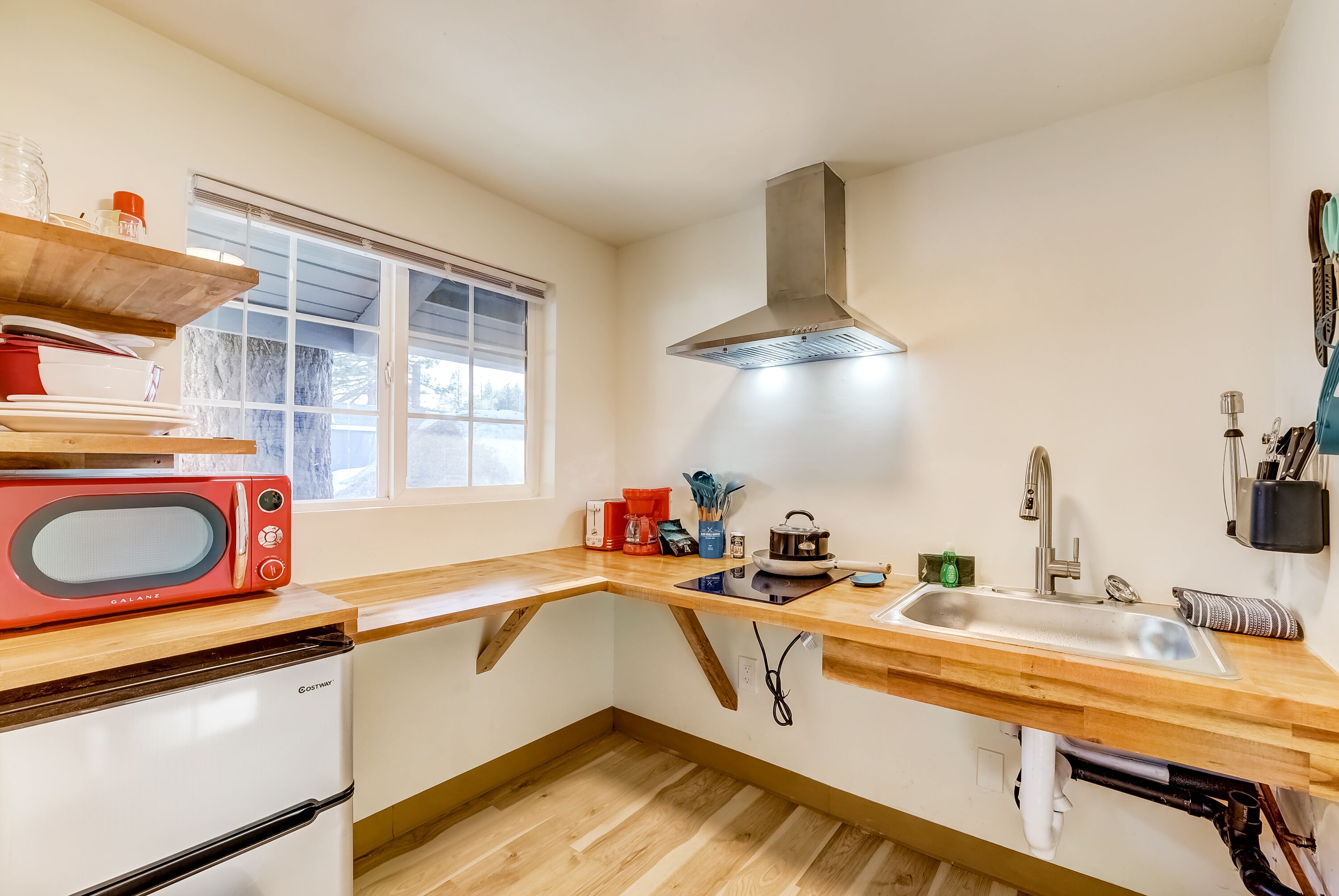 Una cocina compacta con microondas, pileta y cocina.