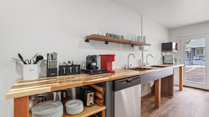 Una cocina moderna con encimera de madera, lavavajillas, cafetera y fregadero.