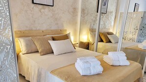 Hotellihuone, jossa on suuri sänky, kaksi yöpöytää, peili ja koristeellinen sermi.