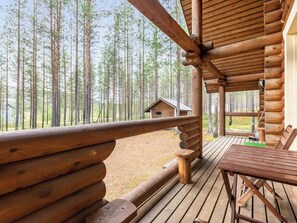 Une terrasse en bois offrant une vue sur une forêt et une petite cabane visible au loin.