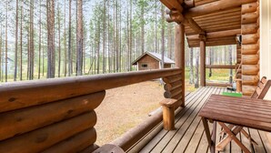 Une cabane en bois dotée d’une terrasse et offrant une vue sur une forêt.