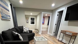 A living room with a black sofa, a coffee table, and a TV. - 3- Bedroom Bungalow 20 Minutes From ND Campus (Elkhart)