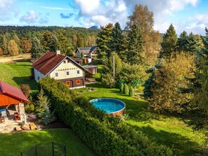 A residential area with a large house featuring a swimming pool, surrounded by lush greenery and a hilly landscape in the background. - Vacation home Kámen by Interhome (Arnoltice)