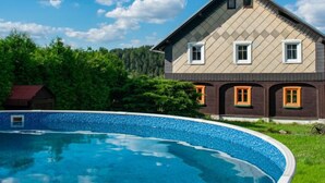 A two-story house with a swimming pool in front.