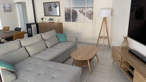 A modern living room with a grey sectional sofa, a wooden coffee table, a TV stand, and a dining area with a table and chairs. - House 200m from the beach (La Tranche-sur-Mer)