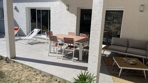 An outdoor patio with a dining table and chairs, a sofa, and a slide. - House 200m from the beach (La Tranche-sur-Mer)