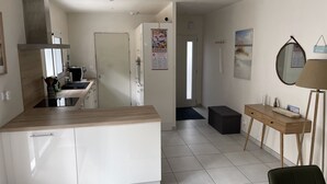 A modern kitchen with white cabinets, a wooden countertop, and a dining area with a small table and chairs. - House 200m from the beach (La Tranche-sur-Mer)