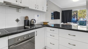 Eine moderne Küche mit weißen Schränken, einer schwarzen Arbeitsplatte und einem eingebauten Backofen.