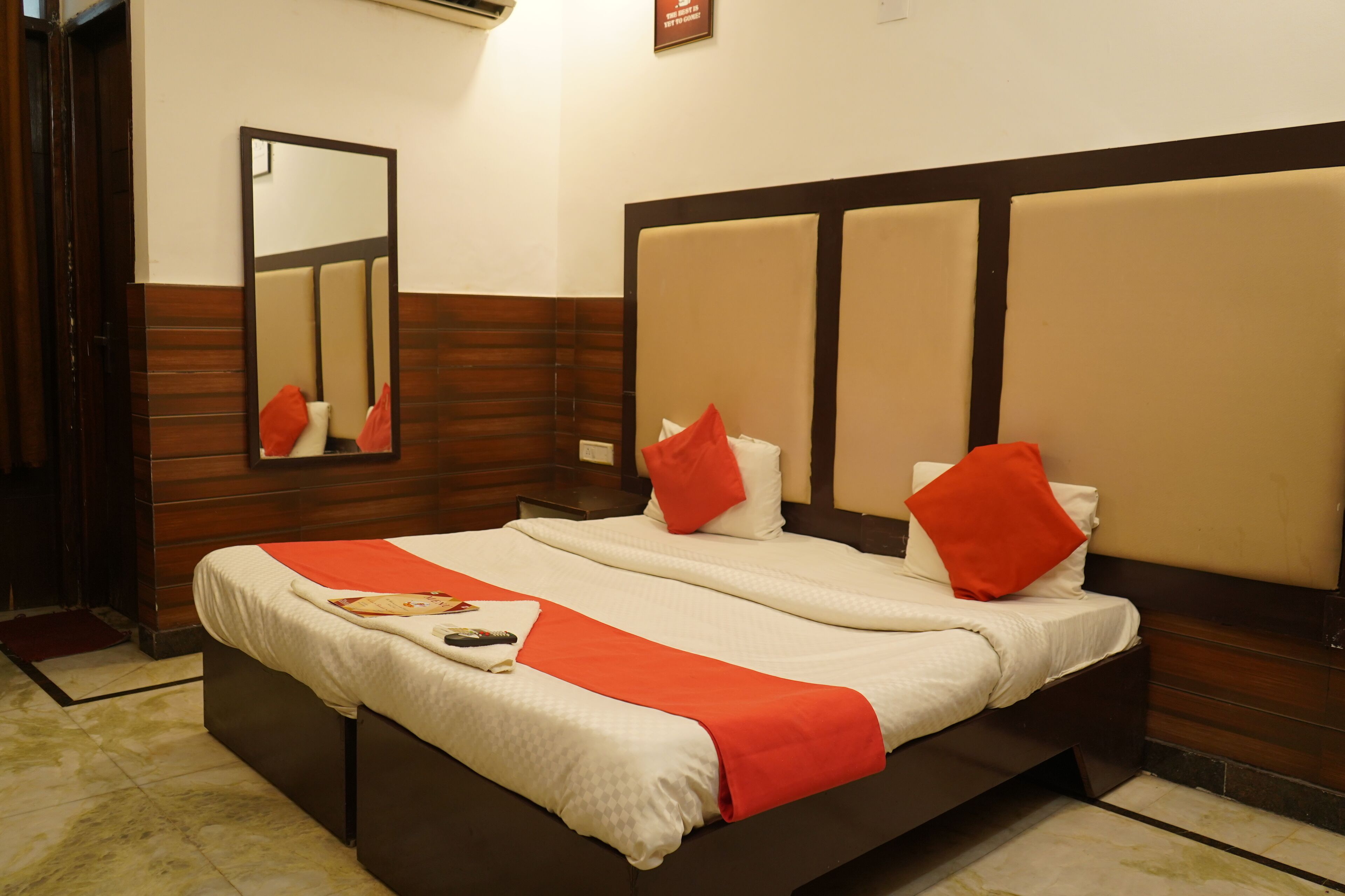 A hotel room with a large bed, a mirror, and a wooden headboard.