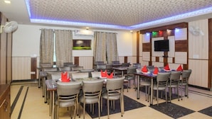 A conference room with a patterned ceiling, multiple tables with chairs, and a television on the wall. - Hotel J. Palace (New Delhi)