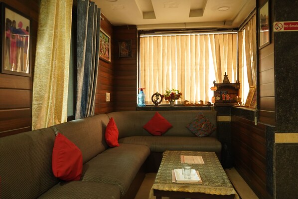 A cozy room with a sofa, a small table, and a window with curtains.