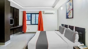 A hotel room with a large bed, a TV, a desk, and a window with curtains. - Hotel J. Palace (New Delhi)