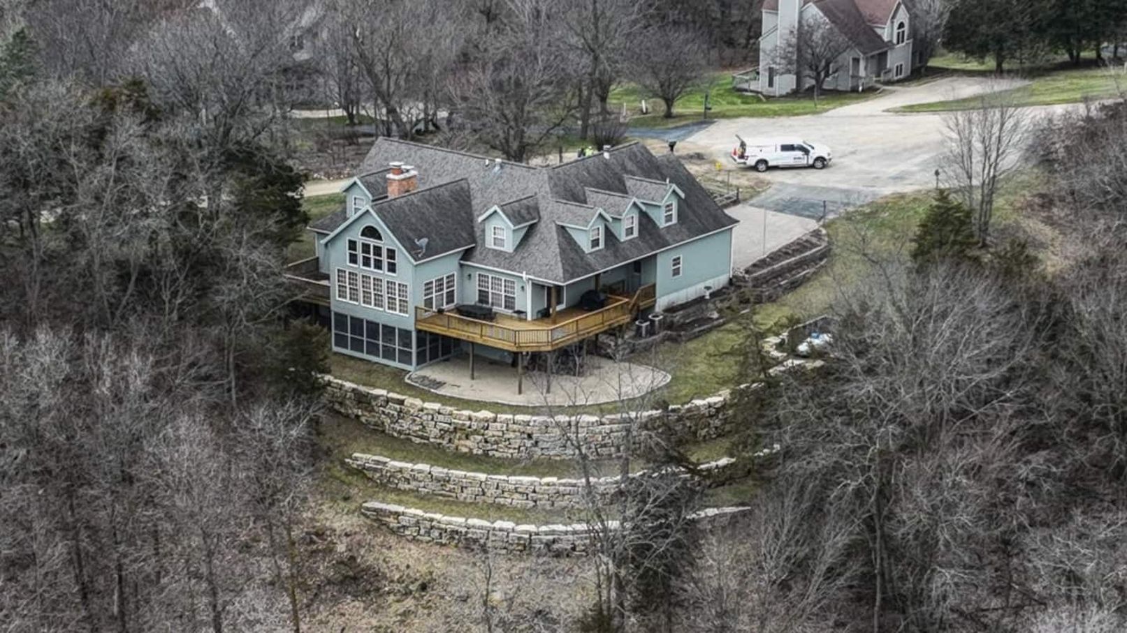 A large, two-story house with a prominent front porch and a stone retaining wall.