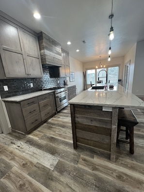 Una cocina moderna con una isla grande, armarios de madera y salpicadero de piedra.