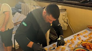 A chef preparing food on a rooftop terrace with a city view in the background. - PENTHOUSE WITH SEAVIEW TERRACE IN THE CITY'S HEART (Cagliari)