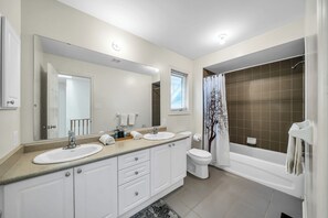 Een bad/douchecombinatie, handdoeken, zeep, toiletpapier