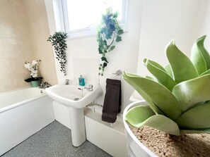 Bañera con ducha, toallas, papel higiénico