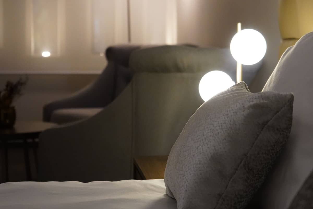 Une chambre d’hôtel avec un lit, une chaise et un lampadaire.