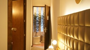 A hotel room with a wooden door, a bed with a headboard, and a small potted plant in the background. - Antigua Hotel Boutique (Atizapan de Zaragoza)
