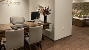 A hotel reception area with a reception desk, chairs, a vase with flowers, a wall-mounted TV, and a reception sign. - Antigua Hotel Boutique (Atizapan de Zaragoza)