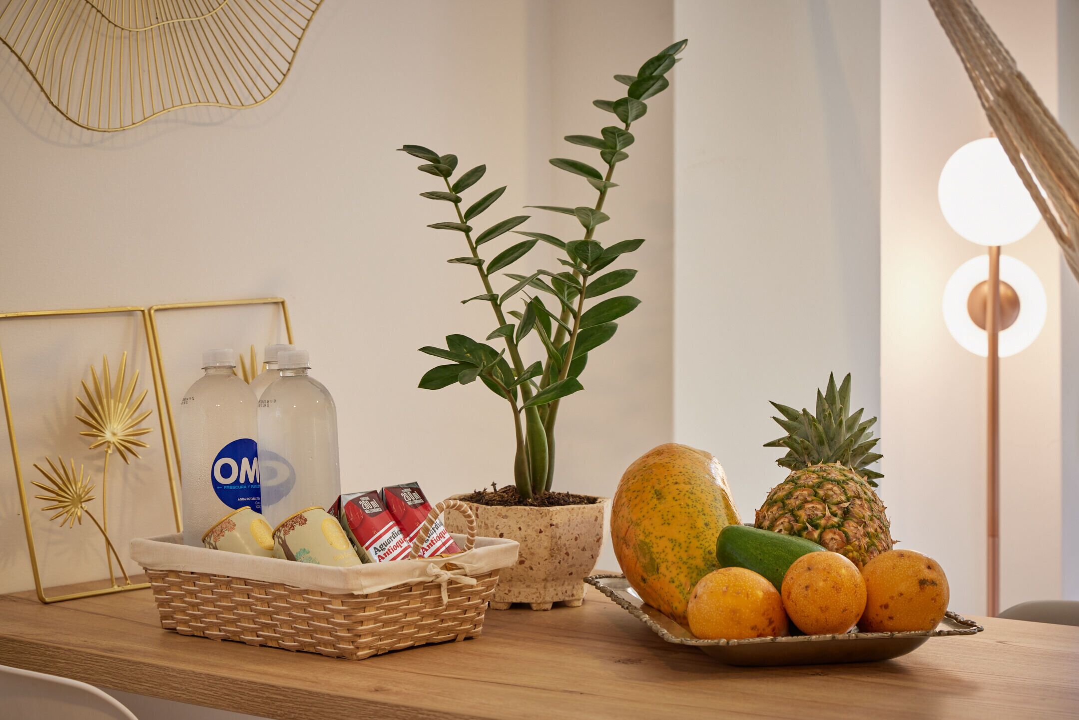 Una taula amb una planta en test, un cistell d'aperitius i un plat de fruita.