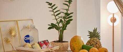Una taula amb una planta en test, un cistell d'aperitius i un plat de fruita.