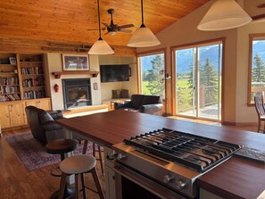 A spacious kitchen with a central island, a dining area with a sofa, and a fireplace. - Large Bigfork Home, summer availability! Mountain Views-Family friendly! (Bigfork)