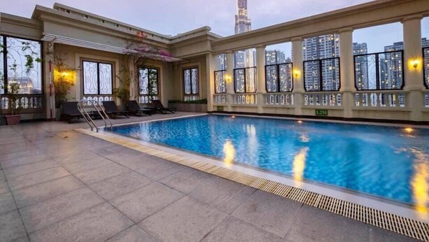 A swimming pool with a view of a tall building in the background. - The Manor  Apartment Nguyen Huu Canh (Ho Chi Minh City)