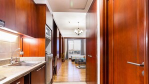 A narrow hallway with wooden cabinets and a kitchen area on the left. - The Manor  Apartment Nguyen Huu Canh (Ho Chi Minh City)