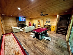 Une pièce chaleureuse avec une table de billard, une cheminée et un téléviseur.