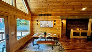 A wooden interior with a dining area, large windows, and a fireplace. - Hidden Creek Cabin Sleeps 8 • Hot Tub • Game Room • 8 Min to Downtown (Blue Ridge)