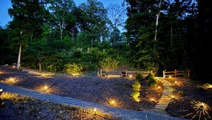 A pathway leading through a forested area with a wooden bench and a small bridge. - Hidden Creek Cabin Sleeps 8 • Hot Tub • Game Room • 8 Min to Downtown (Blue Ridge)