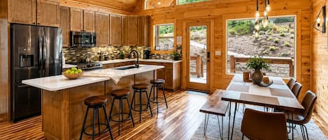A spacious kitchen with a large island, wooden flooring, and a view of the outdoors.