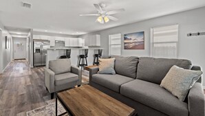 A modern living room with a grey sofa, a wooden coffee table, and a ceiling fan.