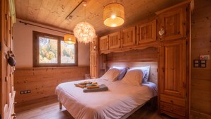 Ein Schlafzimmer einer Holzhütte mit einem großen Bett, zwei Hängelampen und Holzschränken.