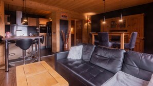 Ein gemütliches Blockhausschlafzimmer mit Ledersofa, Esstisch aus Holz und moderner Küche.