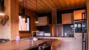 Eine moderne Küche mit Holzschränken, Edelstahlgeräten und Pendelleuchten.